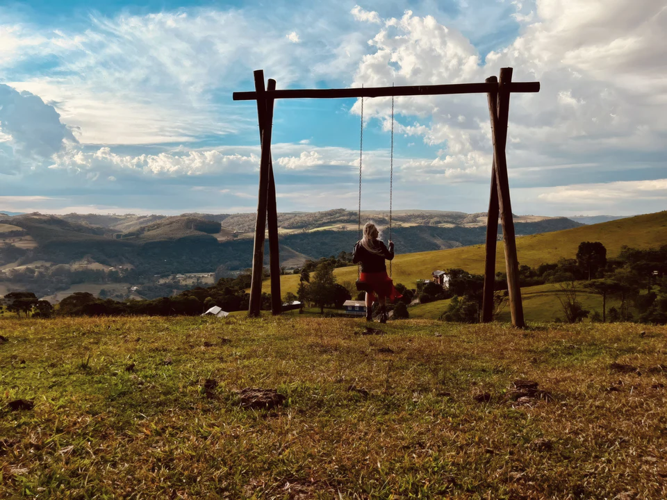 Hóspede no balanço do alto do campo, de frente para o vale