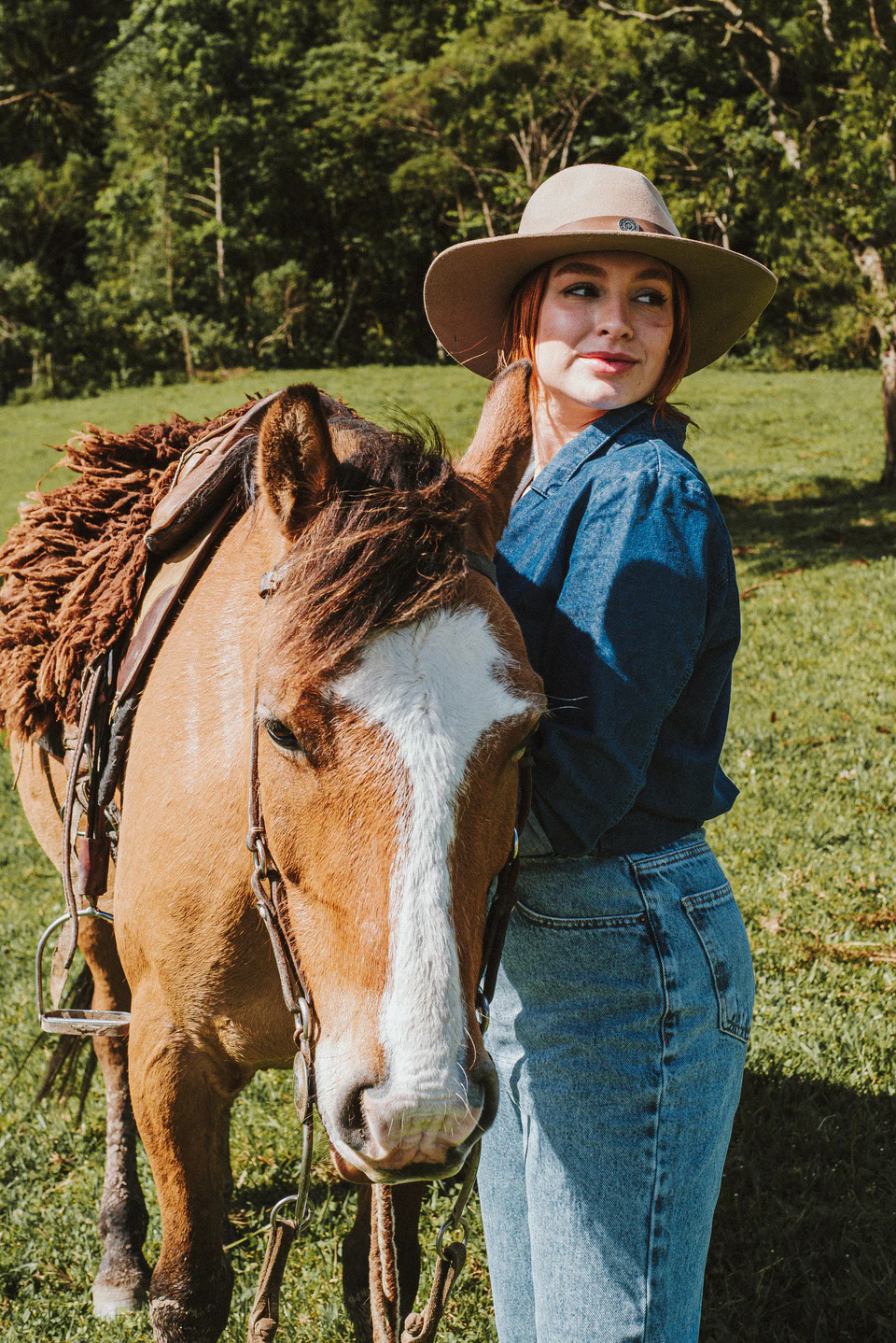 Hóspede ao lado de um cavalo selado no campo